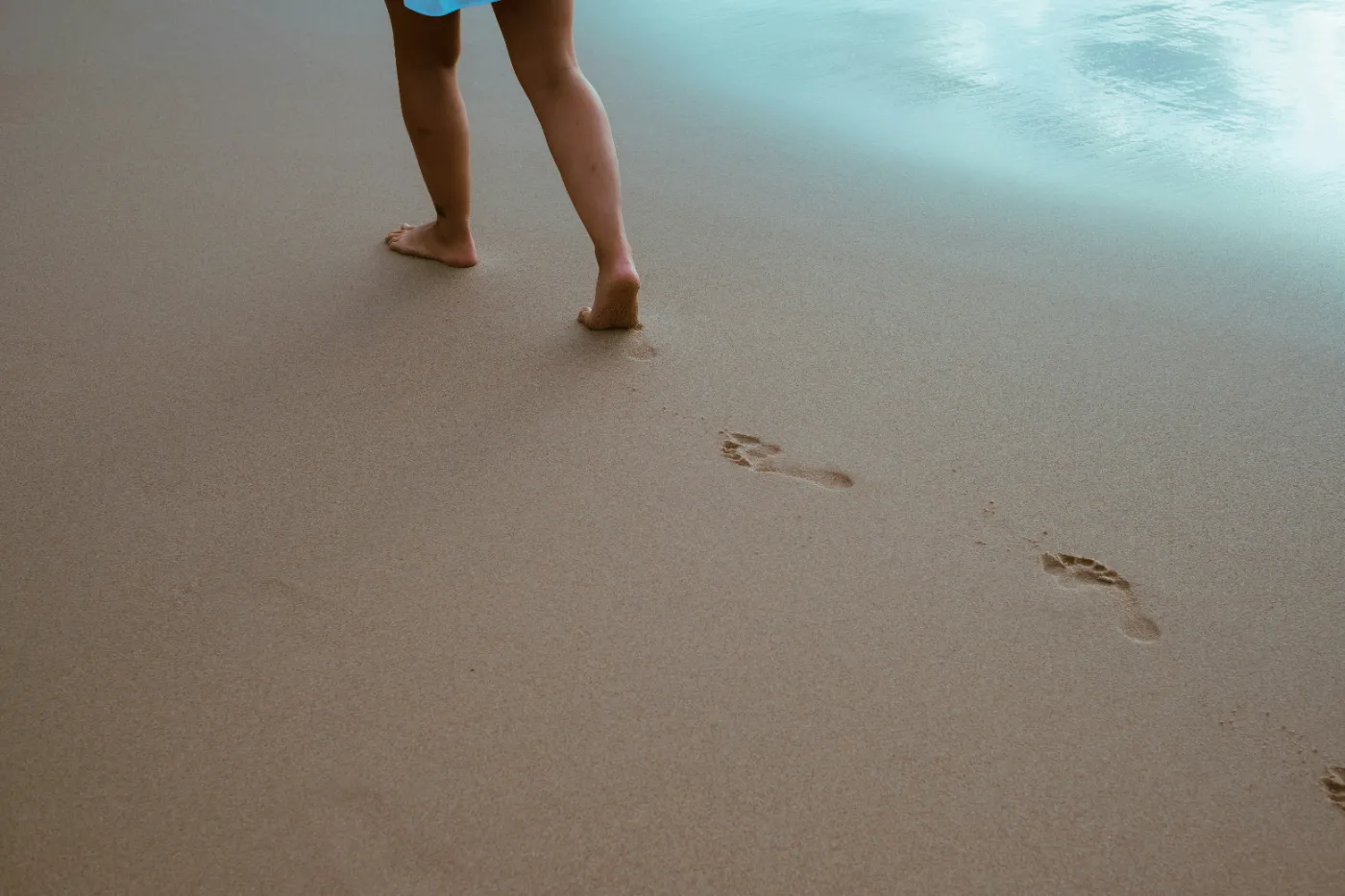 Bare feet walking on smooth sand near the water
